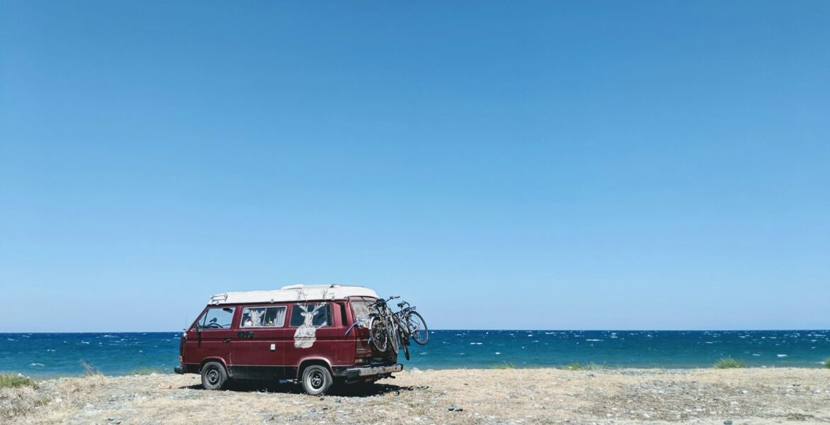 red van near seashore viewing blue sea during daytime