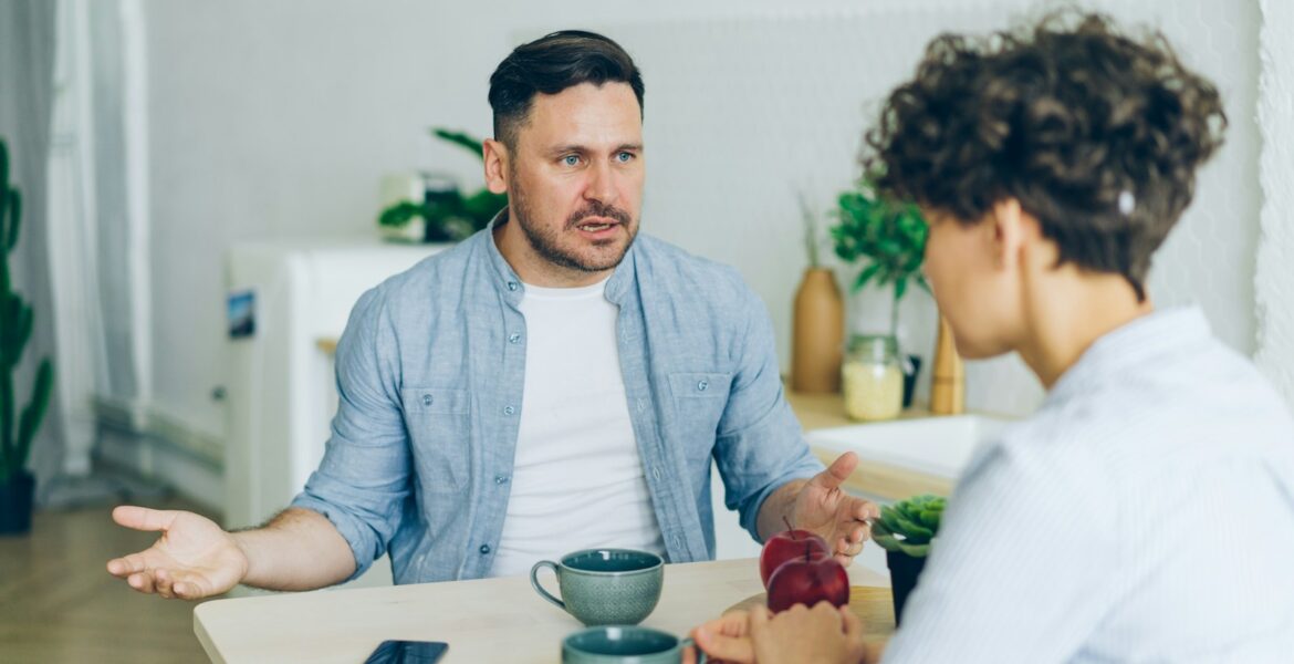 a man sitting at a table talking to a woman